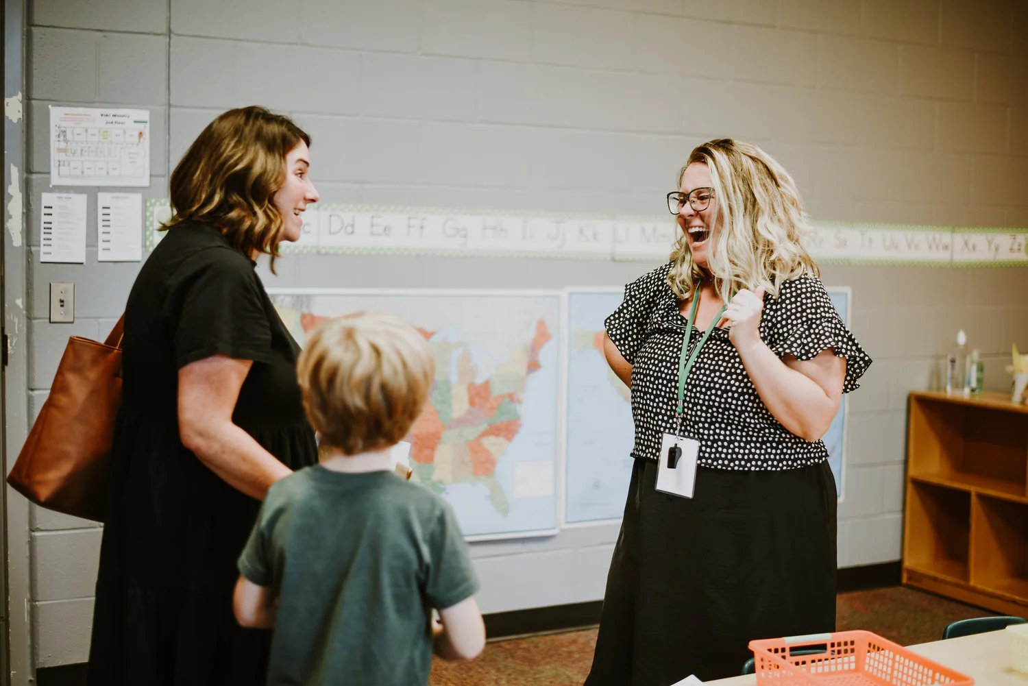 Two teachers greeting a young student